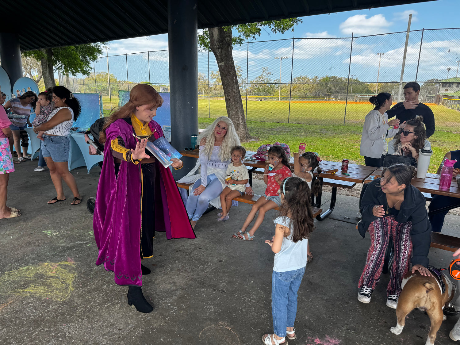 Children and adults at an outdoor birthday event with princess anna and elsa.